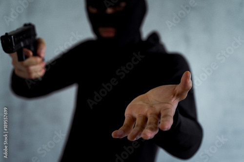 Robber or gangster,thief masked holding gun in hand hide weapon for killed and shoot taking wallet