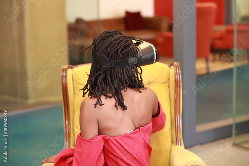 Black female in VR goggles looking back