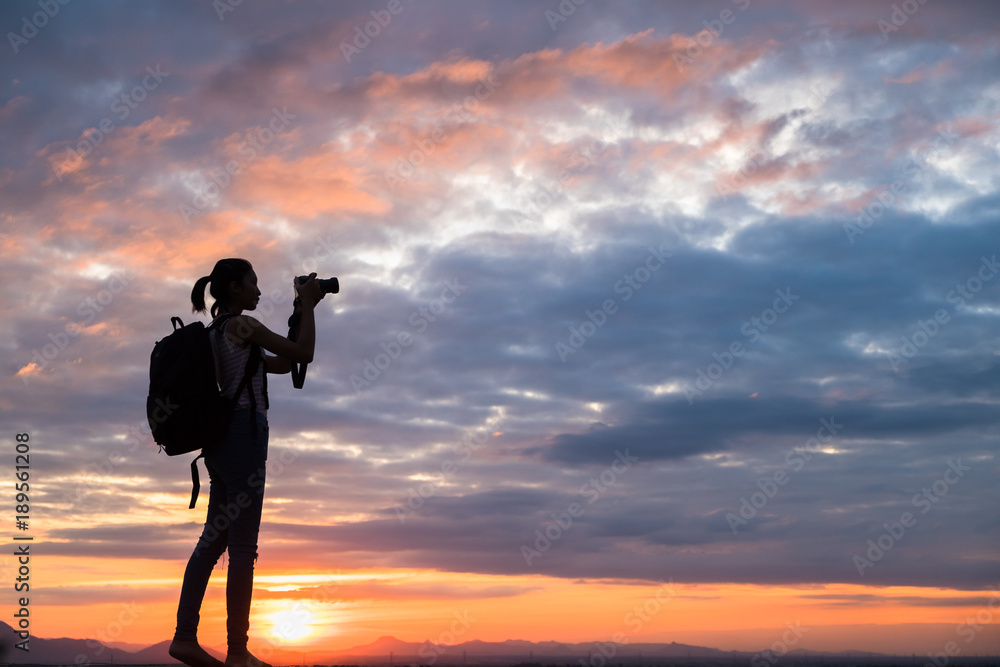 Professional woman photographer taking camera outdoor at sunset