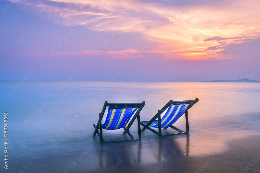 Two beach chairs put on the beach with twilight sky background