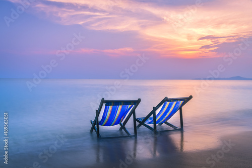 Two beach chairs put on the beach with twilight sky background © APchanel