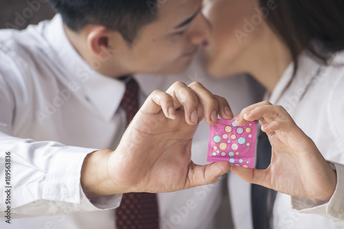 Couple lover showing condom on hand. Safe sex birth control concept.