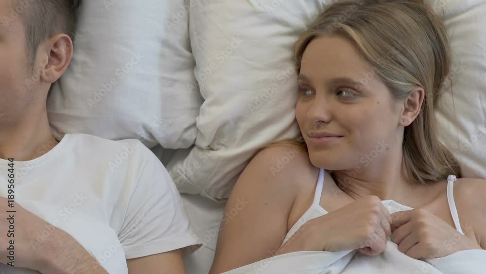 Loving couple under blanket looking embarrassed before first sex, insecurity Loving couple under blanket looking embarrassed before first sex, insecurity