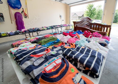 Children's clothing and toys on display at a garage sale