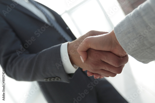 Excited smiling businessman handshaking partner at meeting,