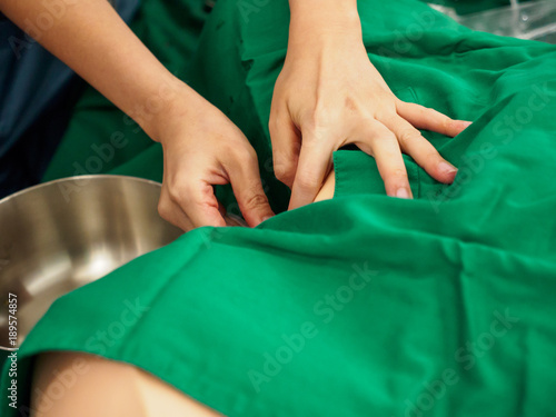 A physician performs a pelvic examination on a dummy practice patient, with sterile drapes and a steel basin. Obstetrics and gynecology concept.