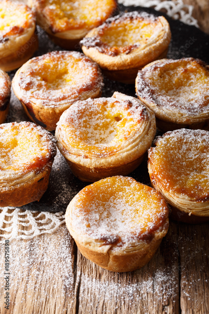 Portuguese cuisine: pastel de nata dessert with a cream and powdered sugar close-up on the table. vertical