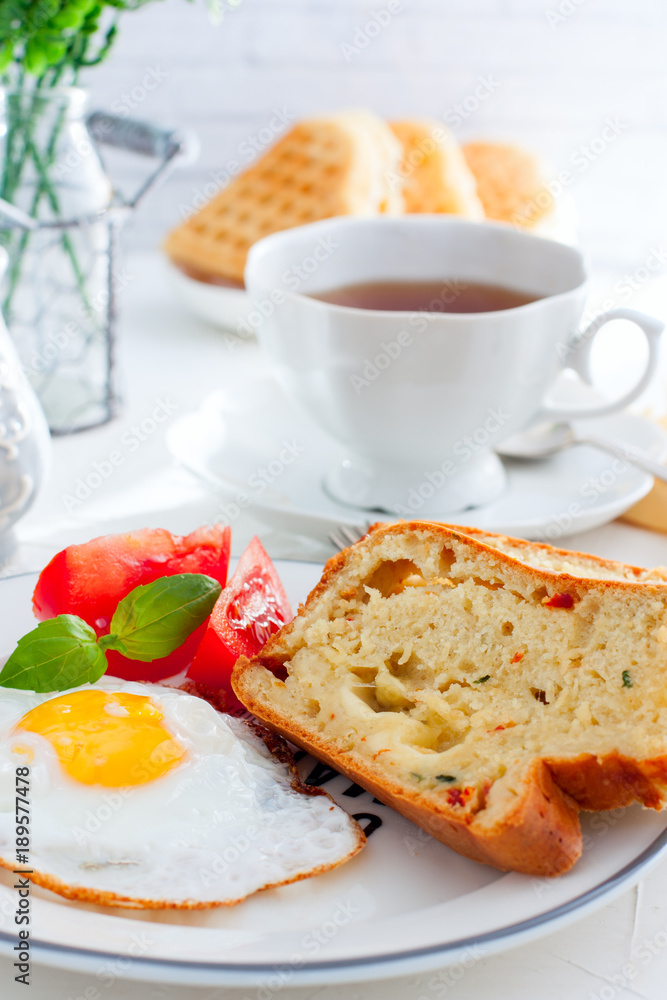 Fresh breakfast with scrambled eggs, fresh tomatoes and sliced pieces of muffins with mozzarella and sun-dried tomatoes, selective focus Fresh breakfast with scrambled eggs, fresh tomatoes and sliced pieces of muffins with mozzarella and sun-dried tomatoes, selective focus