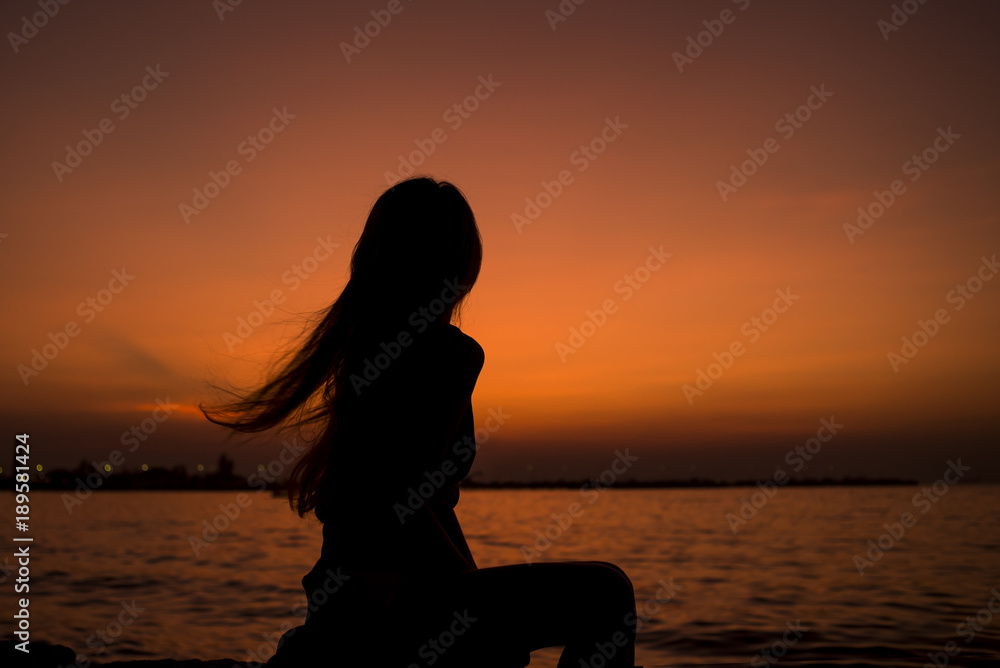Silhouette of Asia Beautiful girl in quiet nature. There is an orange sunset in the background,copy space