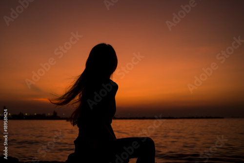 Silhouette of Asia Beautiful girl in quiet nature. There is an orange sunset in the background,copy space © miraclebuggy