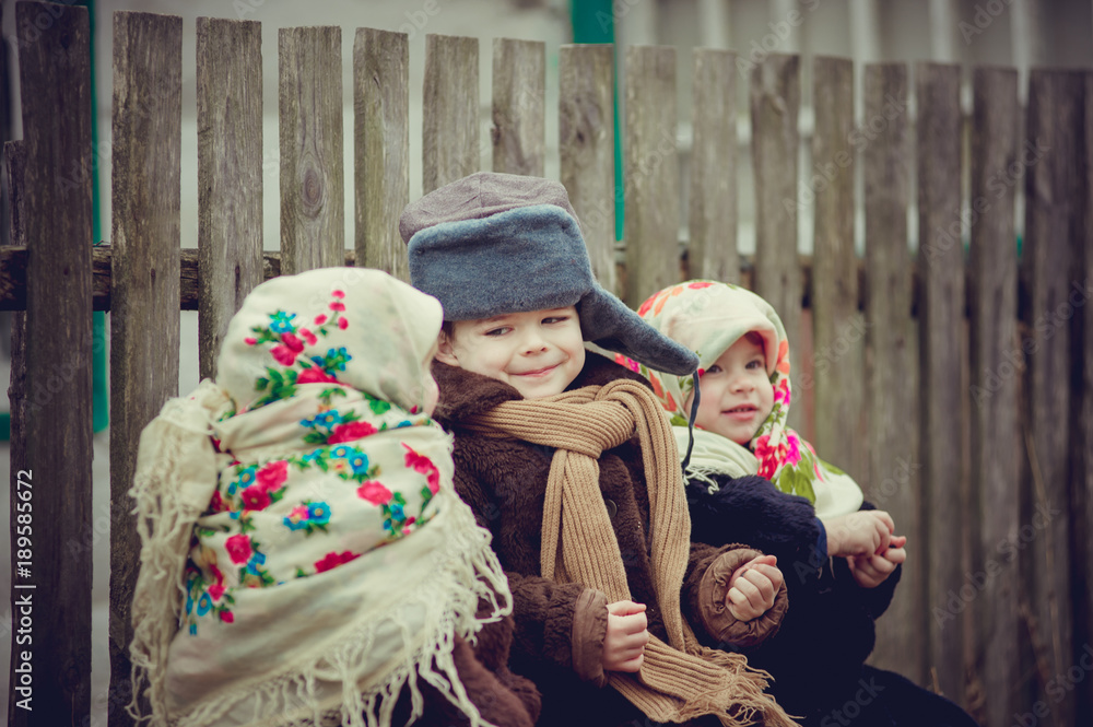 Obraz premium Village children are sitting on the bench under the house and eat seeds