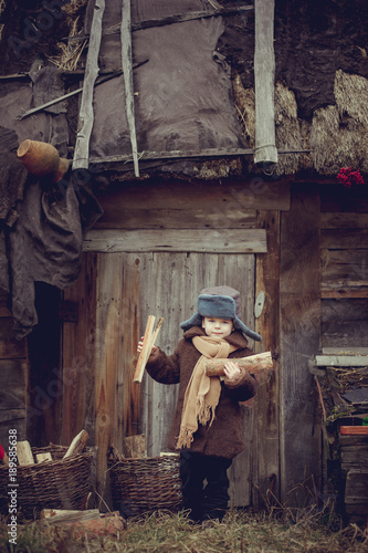 Wallpaper Mural A little boy in an old coat collecting firewood in the yard Torontodigital.ca