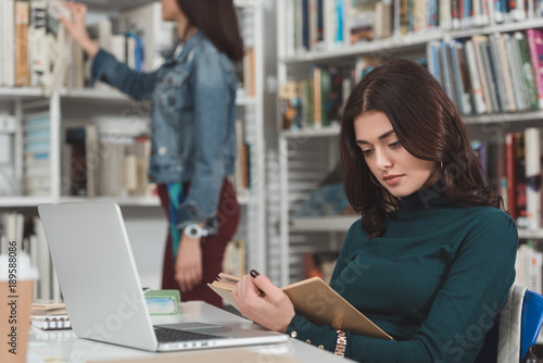 female student reading book in library