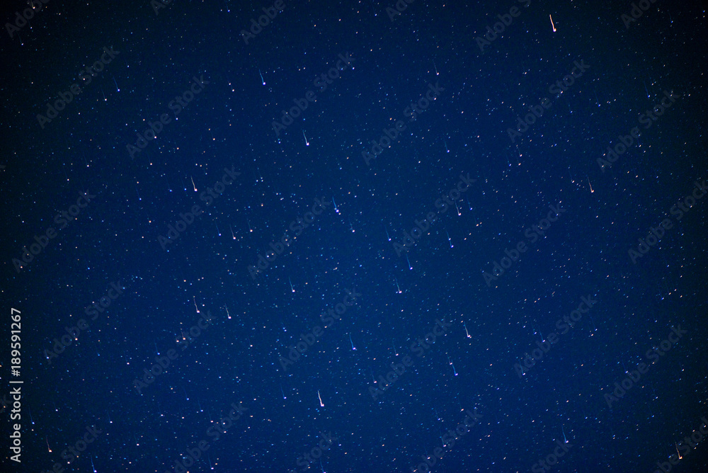Abstract shot of starry sky. Stars are falling on clear blue night-sky. Shooting stars. Falling meteorite or comet with glowing light. Galaxy sky background. Perseid Meteor Shower Abstract shot of starry sky. Stars are falling on clear blue night-sky. Shooting stars. Falling meteorite or comet with glowing light. Galaxy sky background. Perseid Meteor Shower