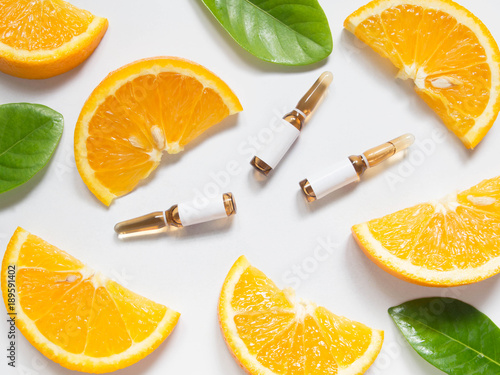 Canvas Print Vitamin C brown ampule for injection with fresh juicy orange fruit slices on white table