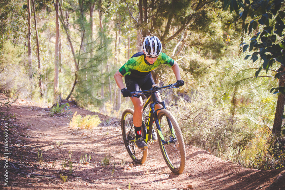 Wide angle view of a mountain biker speeding downhill on a mountain bike track in the woods Wide angle view of a mountain biker speeding downhill on a mountain bike track in the woods