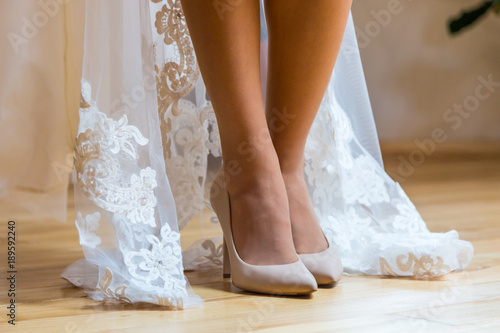 Sexual legs of the bride. The bride is standing on a wooden floor, shoe in cream shoes, and she shows her beautiful legs