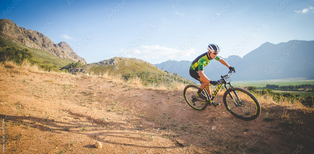 Wide angle view of a mountain biker speeding downhill on a mountain bike track in the woods