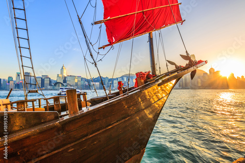 Sunset over Victoria Harbour, Hong Kong harbour with tourist junk, Tsim Sha Tsui, Kowloon, Hong Kong, China. photo