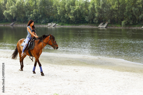 Женщина катается на лошади вдоль реки.