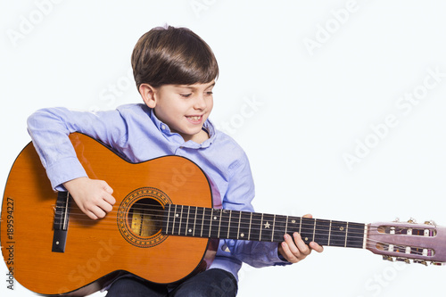 Little boy is playing the guitar isolated in white