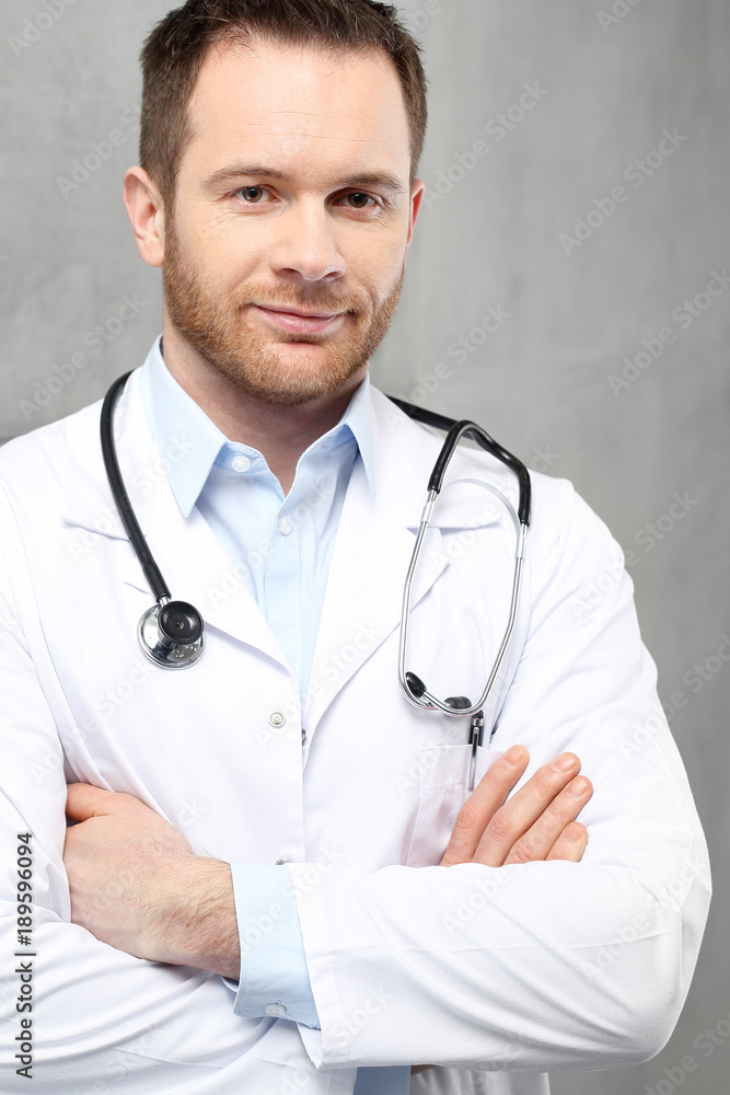 Uśmiechnięty młody lekarz
Przystojny lekarz ubrany w biały kitel stoi w klinice
 - obrazy, fototapety, plakaty 