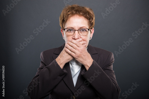 Business senior lady holding hand over mouth