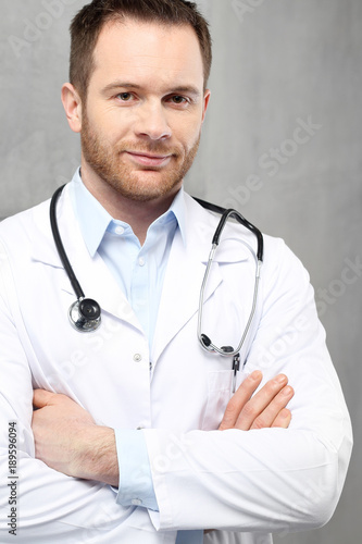 Uśmiechnięty młody lekarz Przystojny lekarz ubrany w biały kitel stoi w klinice 