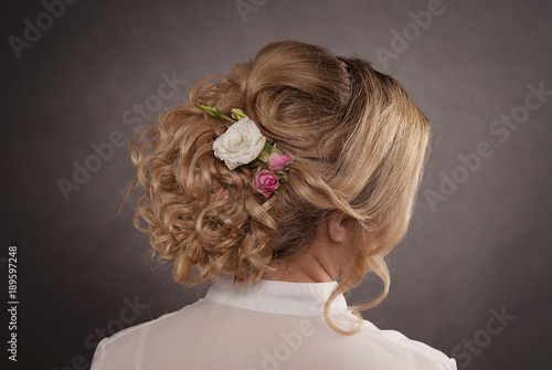 head of blonde woman with hair in wedding bun on gray isolated background rear view