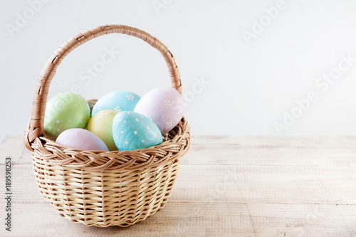 Photography Colorful easter eggs in basket on wooden table