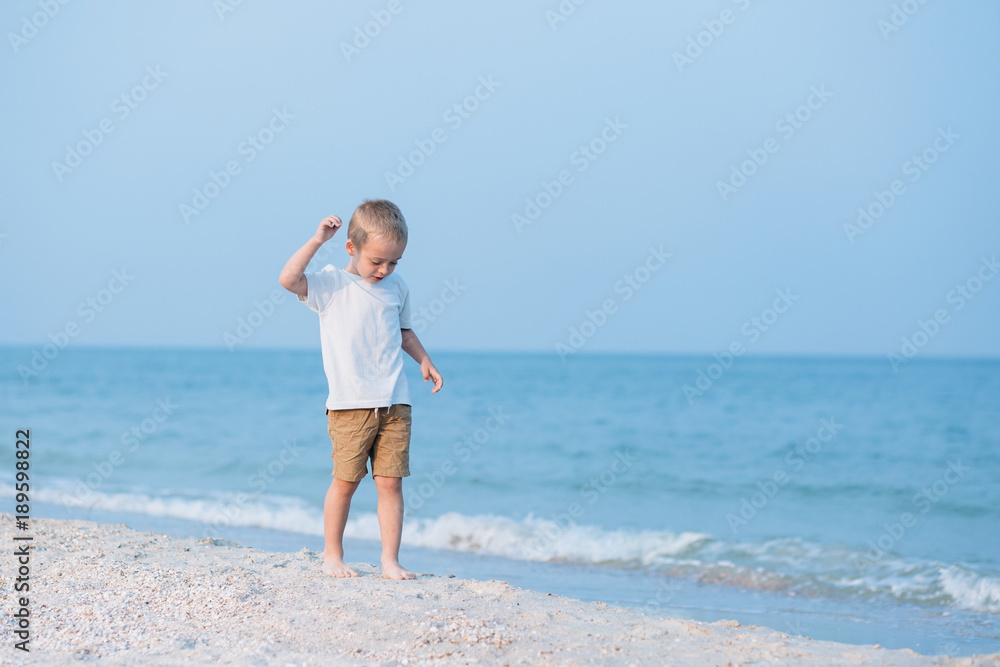 Summer vacation - Portrait of lovely boy walking on the beach near water Summer vacation - Portrait of lovely boy walking on the beach near water