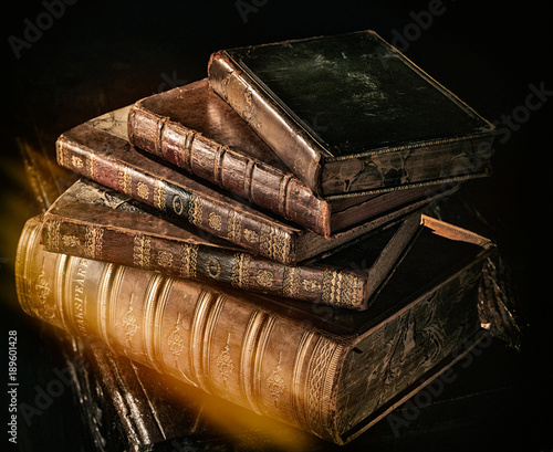 Old books stack in directional light with light leak.
