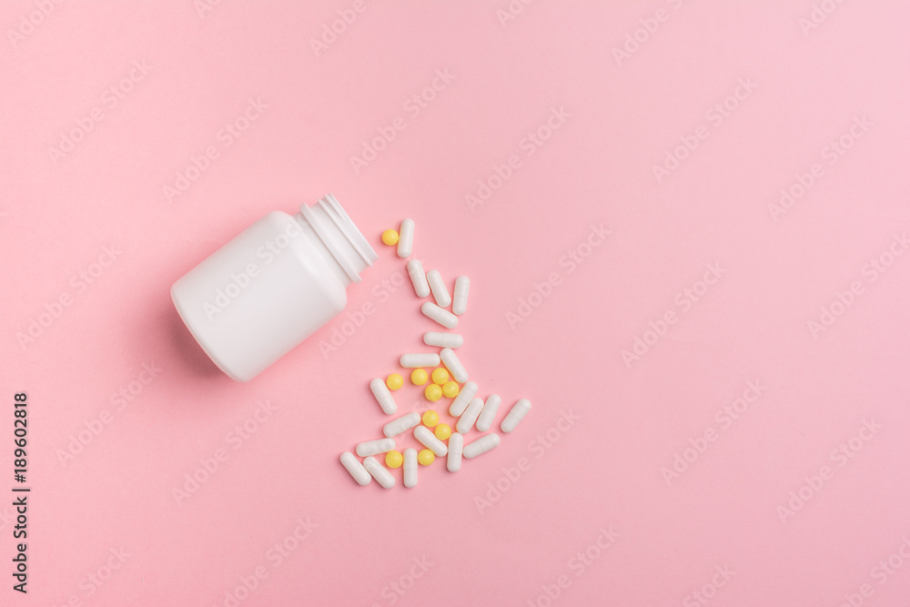 Creative concept Illness:  vitamins in a jar on pink background