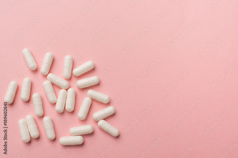 Illness concept: tablets on a pink background top view Illness concept: tablets on a pink background top view