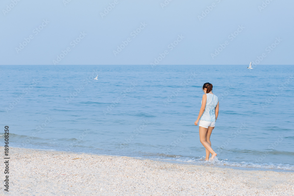 Happy woman on the beach. Portrait of the beautiful girl close-up, the wind fluttering hair. Spring portrait on the beach. Summer portrait