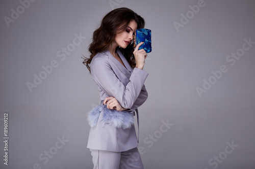 Beautiful woman lady spring autumn collection glamor model business office fashion clothes wear formal dress code style lilac color suit jacket pants accessory bag pretty face hair background studio.