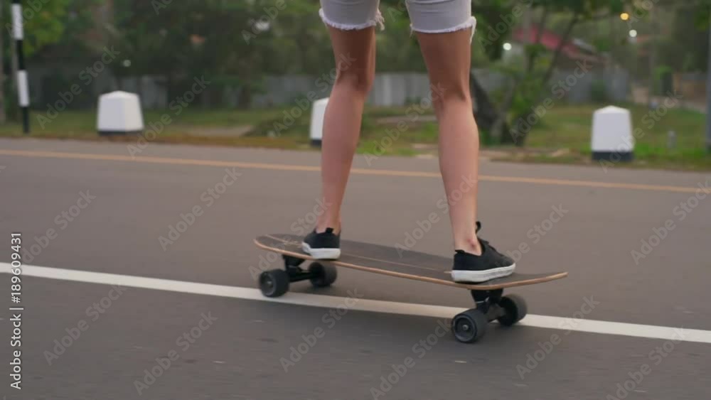 Close up legs of boy and girl skateboarding bridge sunset rapid slow motion Close up legs of boy and girl skateboarding bridge sunset rapid slow motion