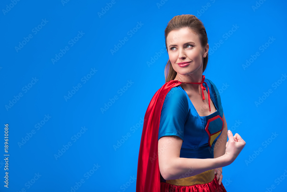 portrait of pensive woman in superhero costume showing muscles isolated on blue portrait of pensive woman in superhero costume showing muscles isolated on blue