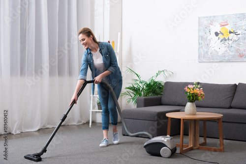 attractive woman with vacuum cleaner cleaning room at home
