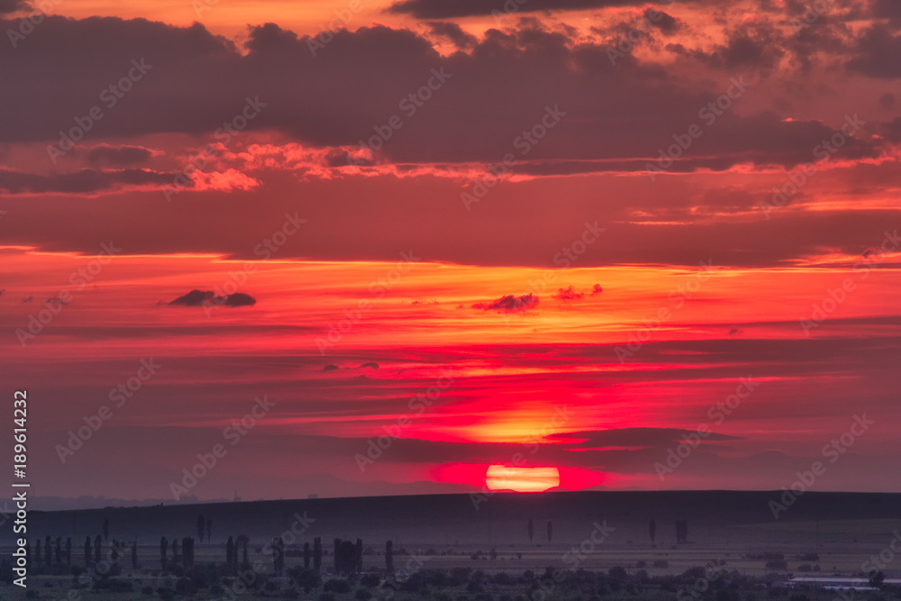 Obraz premium Beautiful rural landscape with a big red setting sun over the fields, Dobrogea, Romania