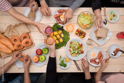 Enjoying dinner with friends. Top view of group of people having dinner together while sitting at wooden table