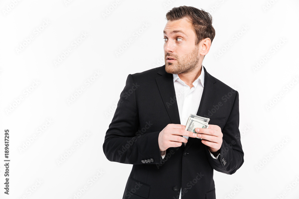 Confused young businessman holding money. Looking aside. Confused young businessman holding money. Looking aside.