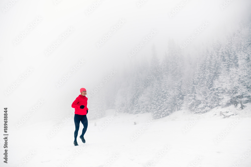 Winter running woman on snow in white mountains