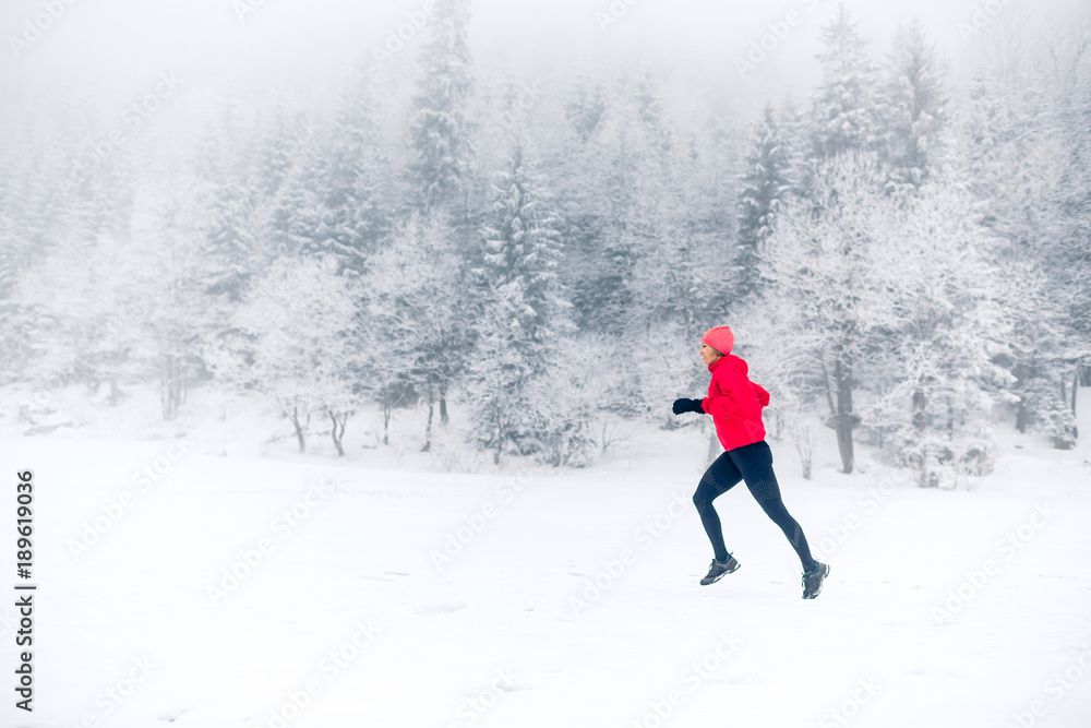 Girl trail running on snow in winter mountains