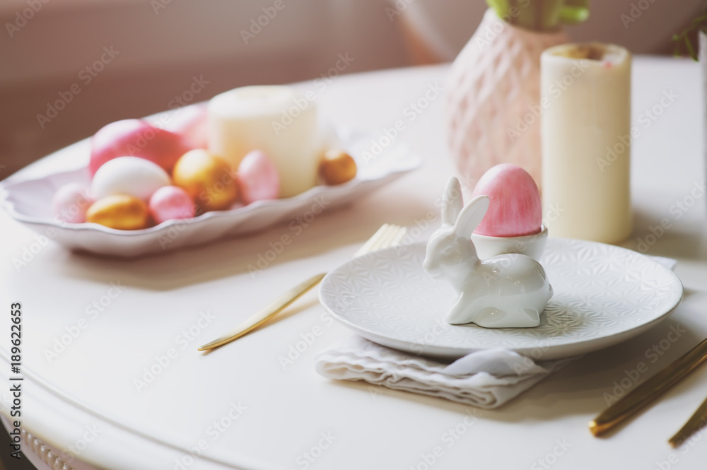 easter festive table details. Dining place decorated in trendy scandinavian style, pink and gold tones, with flowers, candles, bunny and eggs. easter festive table details. Dining place decorated in trendy scandinavian style, pink and gold tones, with flowers, candles, bunny and eggs.