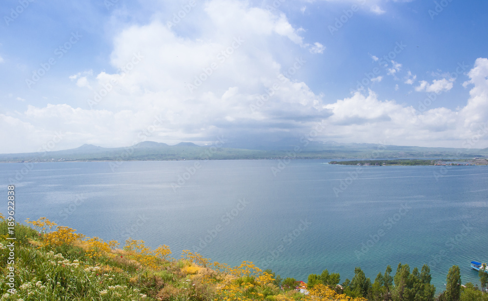 Lake Sevan in Armenia. View of the lake, the horizon and clouds. Yellow wildflowers.	