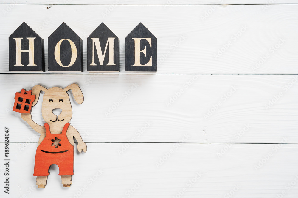 Word Home and dog with gift  on white wooden background with copy space. Home word concept. Home word written on black wooden houses.