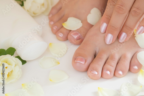 Beautiful groomed woman's hands applying a feet moisturizing cream. Cares about clean, beautiful and soft foot skin. Manicure and pedicure beauty salon. Healthcare concept.