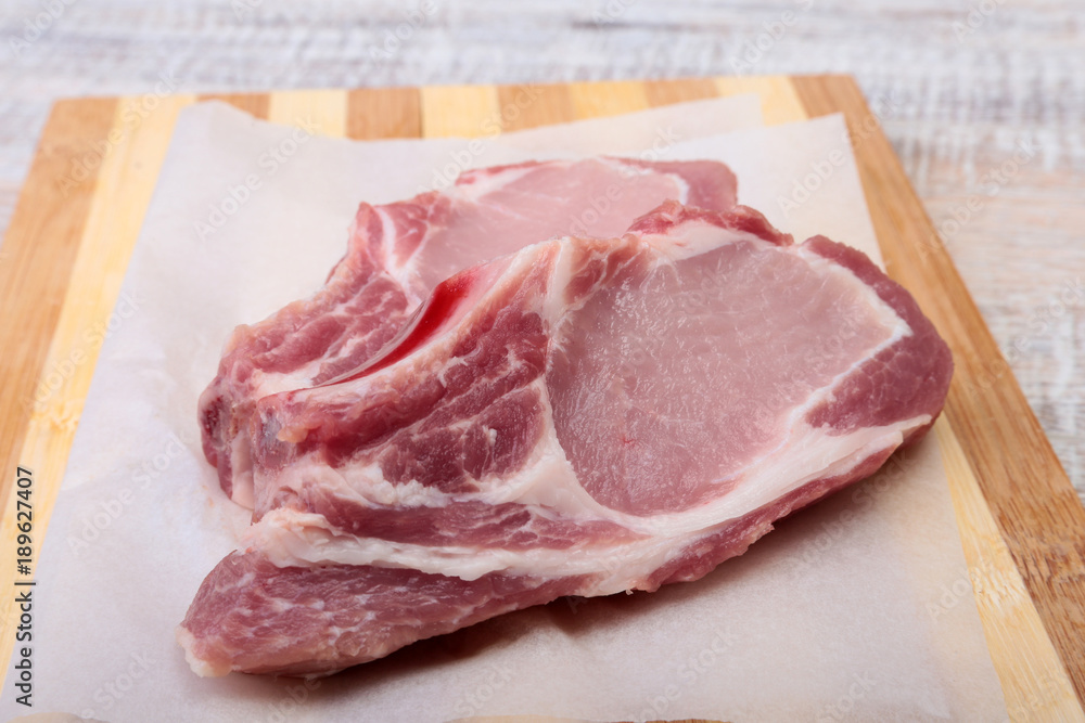 Raw pork chops, spices on cutting board. Ready for cooking. Raw pork chops, spices on cutting board. Ready for cooking.