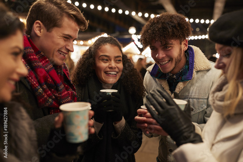 Group Of Friends Drinking Mulled Wine At Christmas Market photo